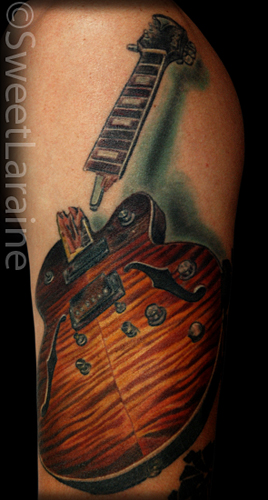 upper arm tattoos. guitar on his upper arm.